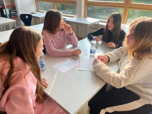 Schülerinnen und Schüler der 7. Klassen sitzen gemeinsam am Tisch und diskutieren.ige